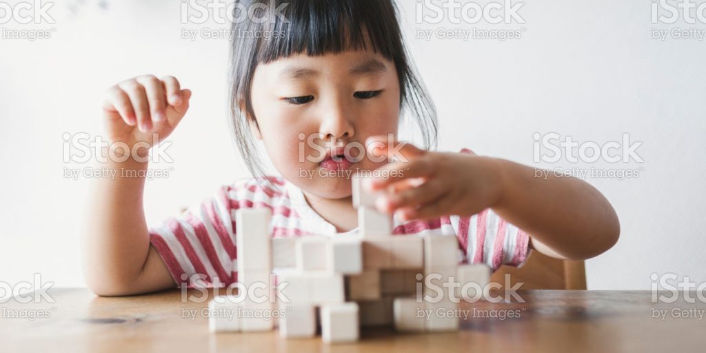 Asian girl studying with blocks on the table in the living room.